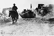 B&W photo of a man on a horse with a tank behind him