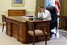  Barack Obama on the phone while sitting at the Resolute desk in 2009. The wooden box holding the button is visible next to the phone.