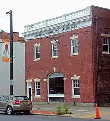 A two-story brick building, similar to but smaller than the house, with an arched entry in the middle
