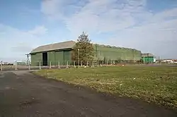A large green, steel clad hangar