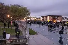 Protesters on the street outside the Brooklyn Center police department as law enforcement stand on the other side of a fence