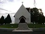 A square with small pine trees with a staircase leading to a chapel