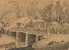 drawing of a wooden building with a water wheel behind a log bridge