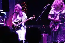 Band members play music onstage while wearing hospital gowns.