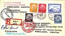 The reverse of a postcard. The consignee's address is in Buenos Aires, Argentina. It bears (on the right, above the address) 25 ℛ︁ℳ︁ worth of postage stamps and a special Deutsche Luftpost stamp for 2 ℛ︁ℳ︁. The stamps are cancelled by a postmark: "Berlin, 26.5.34", and a red cachet saying: "Deutsche Luftpost: Europa-Sudamerika" with a motif of a zeppelin and a Dornier Wal. On the left is the receiving postmark: "Buenos Aires, Argentina 31 May 1934"