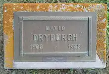 Bronze plaque mounted on a granite base, inscribed with his name, birth year and death year, and a smaller bronze plate attached beneath with his wife's name and dates