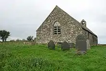 A simple stone church seen almost from the east end. The east window has two lights and a slightly pointed arch, and at the far end the bellcote can be seen
