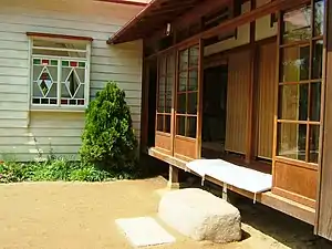 Cushions on an engawa protected by sliding glass doors. Note fume-ishi, stone step.