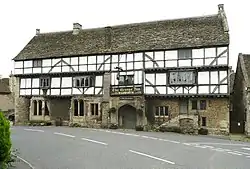 White fronted building with black beams prominent. Over the door is a sign saying The George Inn, Wadworths.
