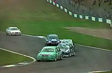Group of five modified road cars in close proximity entering a slightly uphill right turn on tarmac taken from a slightly elevated camera position
