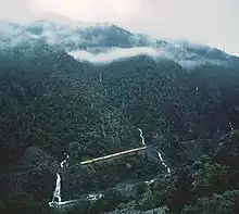 A Union Pacific freight train moving through the Feather River Canyon on a cloudy day, seen from on high.