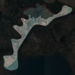 A little island surrounded by brown water and sand.