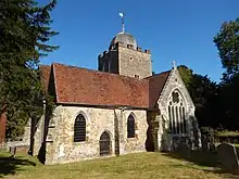 A stone church seen from the south, showing a transept with a large window, and a tower surmounted by a cupola