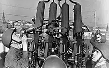 A helmeted soldier adjusts an four barreled anti aircraft gun