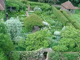 a view of a garden of white flowers with hedging and a boathouse to the right