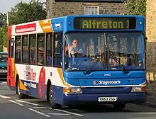 Cropped image to show a close up of front and side of single decker coach size bus on a road facing camera position