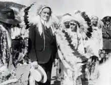 President Coolidge stands with a Native American. Both wear traditional feather headdresses.