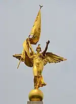 Golden statue of a female angel figure with flag